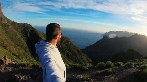 Man with beard climbed to the top and shoot himself. Blue ocean crashes against Stock Footage 156752736