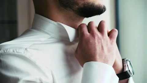 A man with a beard corrects a shirt's collar Video stock 130975922