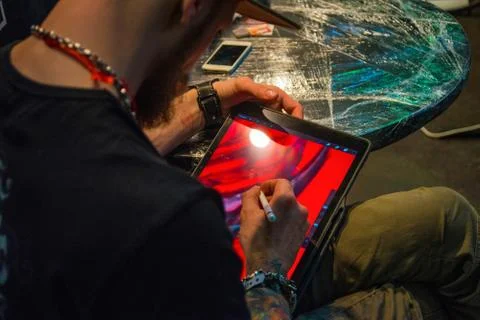 Man with beard creating picture with stilus pencil on tablet screen, freelanc Stock Photos