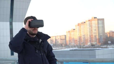 A man with a beard dresses virtual reality glasses on the street on a city backg Stock-Footage 86051596
