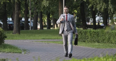 A man with a beard is drinking coffee in the park Stock Footage 117622974