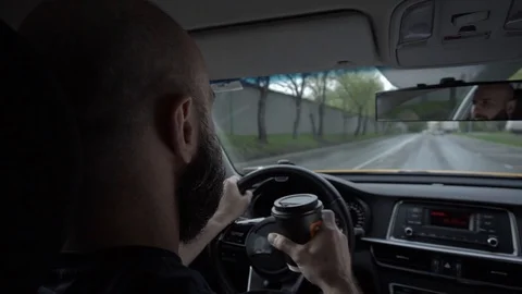 A man with a beard driving and drinking coffee. From back Stock Footage 129968600