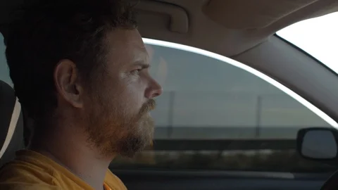 Man with a beard is driving a car with an attentive expression. 4k video Stock Footage 117187002