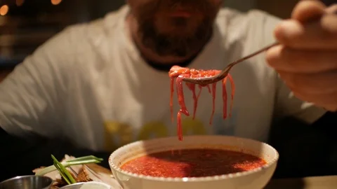 Man with a beard eating borsch with sour cream. red-beet soup. borsh Stock Footage 99789370