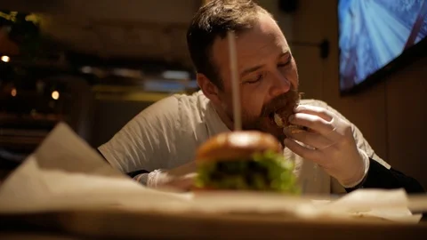 Man with beard eating burger. cheeseburger Stock Footage 99822717