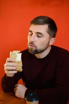 A man with a beard eats shawarma, a quick, tasty and healthy snack at a fas.. Foto stock
