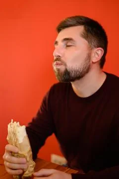 A man with a beard eats shawarma, a quick, tasty and healthy snack at a fas.. Foto stock