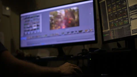 A man with a beard editing video in the program, sitting at two monitors and dri Video stock 98535574