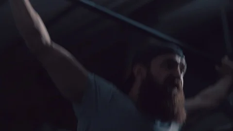 Man with a beard is engaged in weightlifting on a dark background Stock Footage 90642515