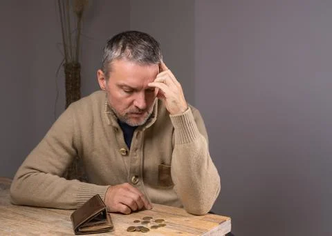 A man with a beard examines small change. A poor middle-aged man Stock Photos