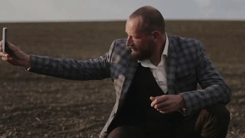 Man with a beard in the field with a phone. 스톡 동영상 76223253