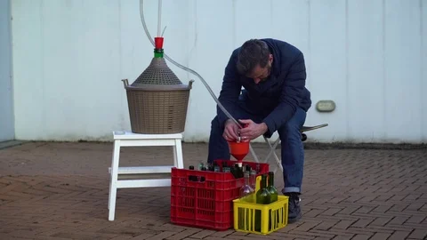 Man with a beard filling some wine bottles with white wine, selective focus Vidéo 79787564