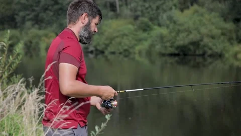 A man with a beard is fishing on the river, casting a line. Stock Footage 159766815