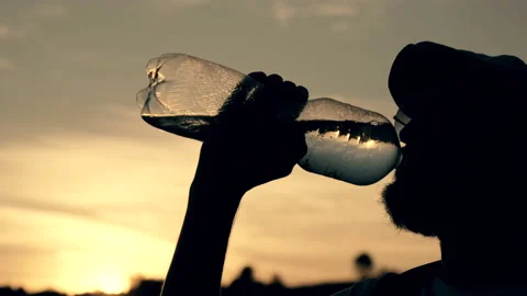 A man with a beard in glasses and a cap drinks water Stock Footage 147052132