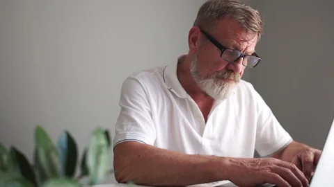 A man with a beard with glasses and a white T-shirt takes notes in his notebook Stock Footage 121451340