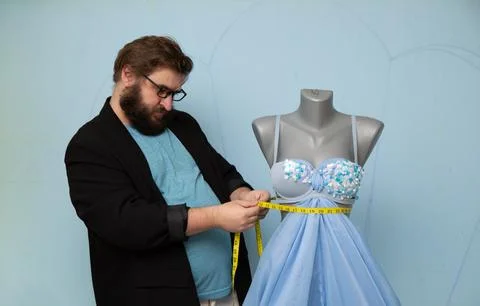 Man with beard, glasses, jacket measures gray mannequin with tailor ruler Stock Photos
