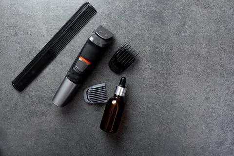 Man beard grooming items on a stone table surface, comb, oil and electric Foto stock