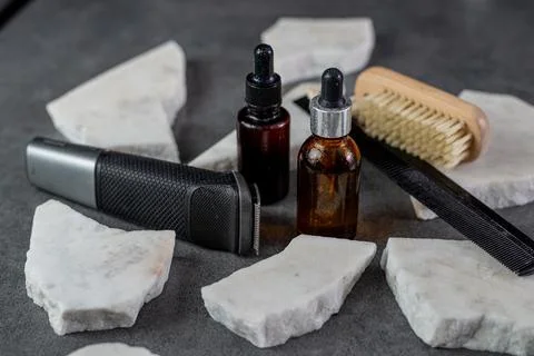 Man beard grooming items on a stone table surface, comb, oil and electric Stock Photos