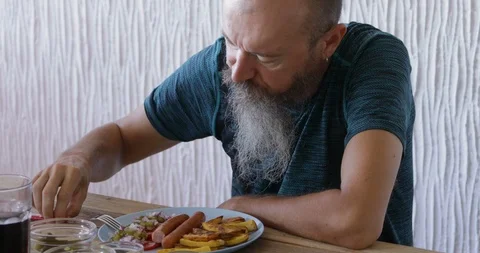Man with beard having breakfast, eating pickled vegetables with hot dog Stock Footage 114966365