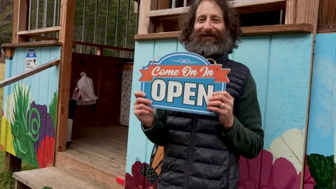 Man with a beard holding an open sign in front of his business Stock Footage 146807776