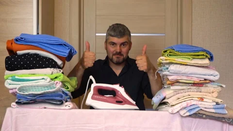 A man with a beard holds in his hands an iron for ironing 4K Stock-Footage 132687138