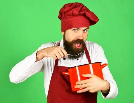 Man with beard holds kitchenware on green background Stock Photos