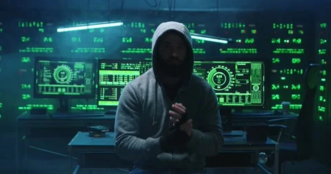Man with beard in hood hacked into database in office while sitting at computer Stock Footage 145290599
