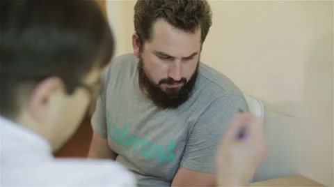 A man with a beard is ill. The guy is sitting in reflexologist office for treatm Stock Footage 68963785
