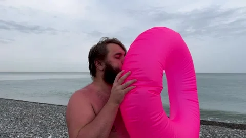 Man with beard inflates pink inflatable ring for swimming Stock Footage 308128049