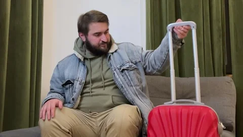 Man with beard in jacket leaves hotel room with red suitcase Video stock 308922464