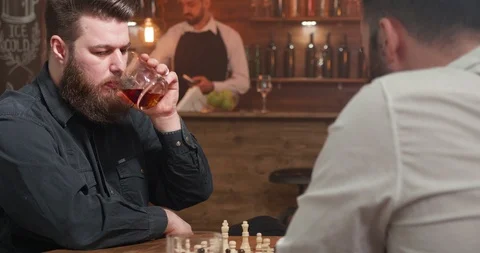 Man with beard looking at the chess board and drinking whiskey Stock Footage 103929110
