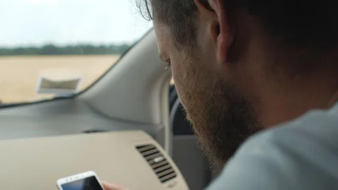 A man with a beard looks into the phone while sitting in the front seat of a car Stock Footage 111281038