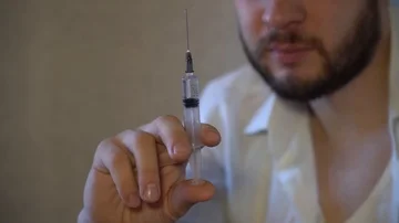 A man with a beard looks at a syringe 스톡 동영상 86044878