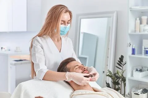 Man with beard is lying on back, getting face lifting massage. Facial massage Stock Photos