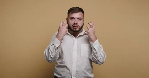 Man with beard makes expressive gestures and faces against a plain backgrou.. 動画素材 326797842