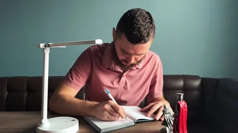 A man with a beard makes notes in a notebook Stock Footage 266508054