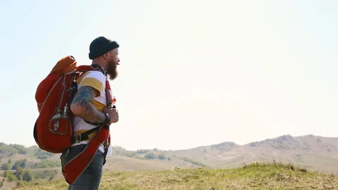 Man with beard mustache with a backpack goes mountains summer looks around. Stock Footage 111237676
