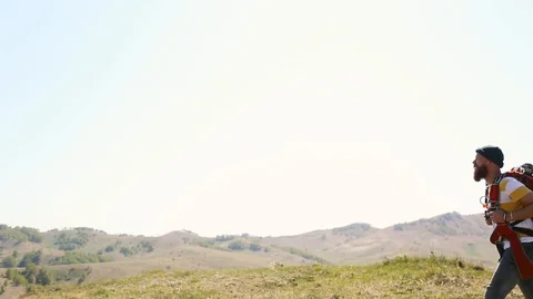 Man with beard mustache with a backpack goes mountains summer looks around. Stock Footage 111237696