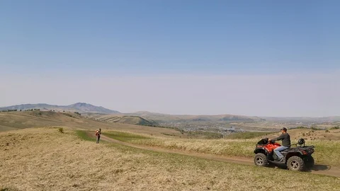 Man with beard mustache with backpack, standing road. ATVs are riding, summer Stock Footage 111237894
