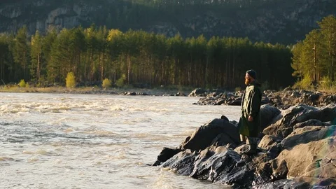 Man beard mustache raincoat is standing near a river with a bucket Stock Footage 111499795