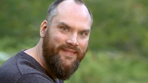 Man with beard outside turns and smiles Stock Footage 129062323