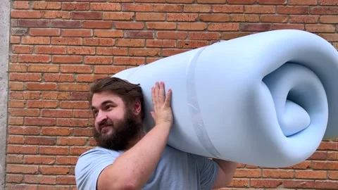 Man with beard picks up and holds blue bundle of soft foam rubber Stock Footage 341275014