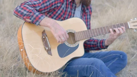 A man with a beard playing the guitar in the field Stock Footage 116245912