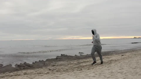 Man with Beard in Protective Face Mask Running by the Beach at Dusk - Wide Dolly Stock Footage 130729236