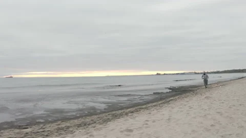 Man with Beard in Protective Face Mask Sprinting by the Beach at Dusk - Wide Stock Footage 130729664