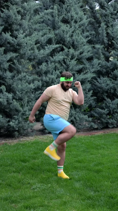 Man with beard raises leg to elbow in city park Stock Footage 307998497