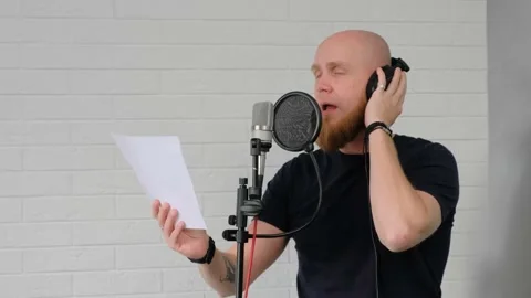 A man with a beard reads paper text in a home music studio. Voice recording. Video stock 139649459