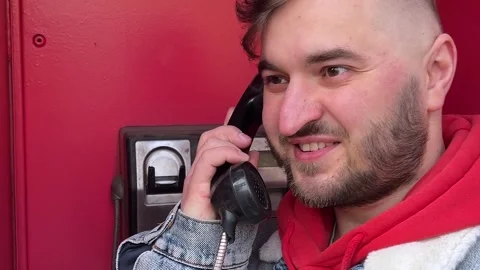 Man with beard in red telephone booth calling to friend Stock Footage 304762182