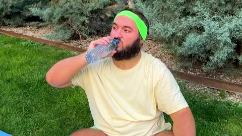 Man with beard rests and drinks water from bottle in park Stock-Footage 319964414