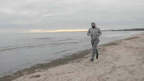 Man with Beard Running by the Beach at Dusk - Wide Dolly Shot Stock Footage 130727763